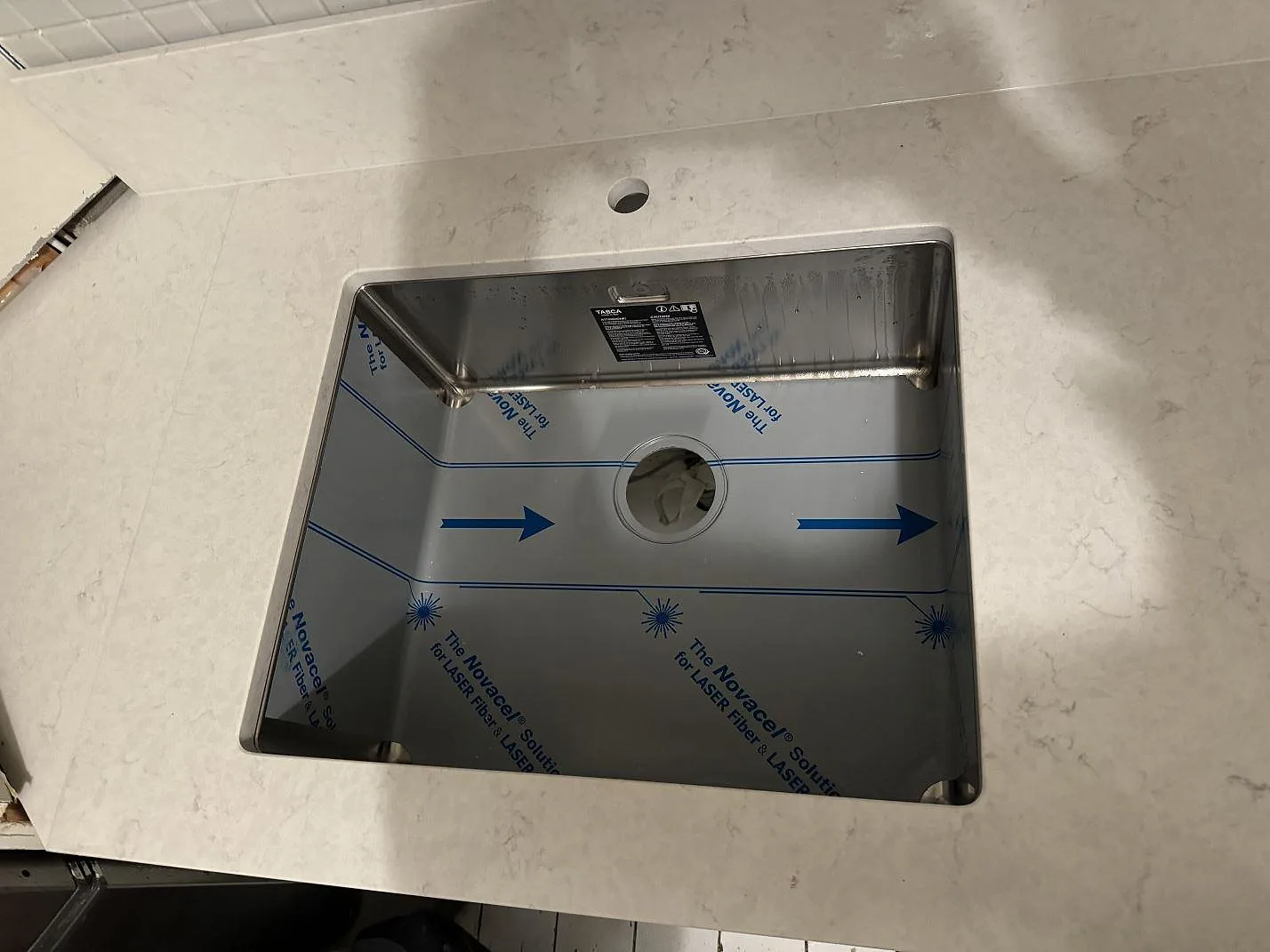 Närbild på underlimmad rostfri diskho i en vit polerad Silestone Snowy Ibiza bänkskiva i ett kök i Göteborg.