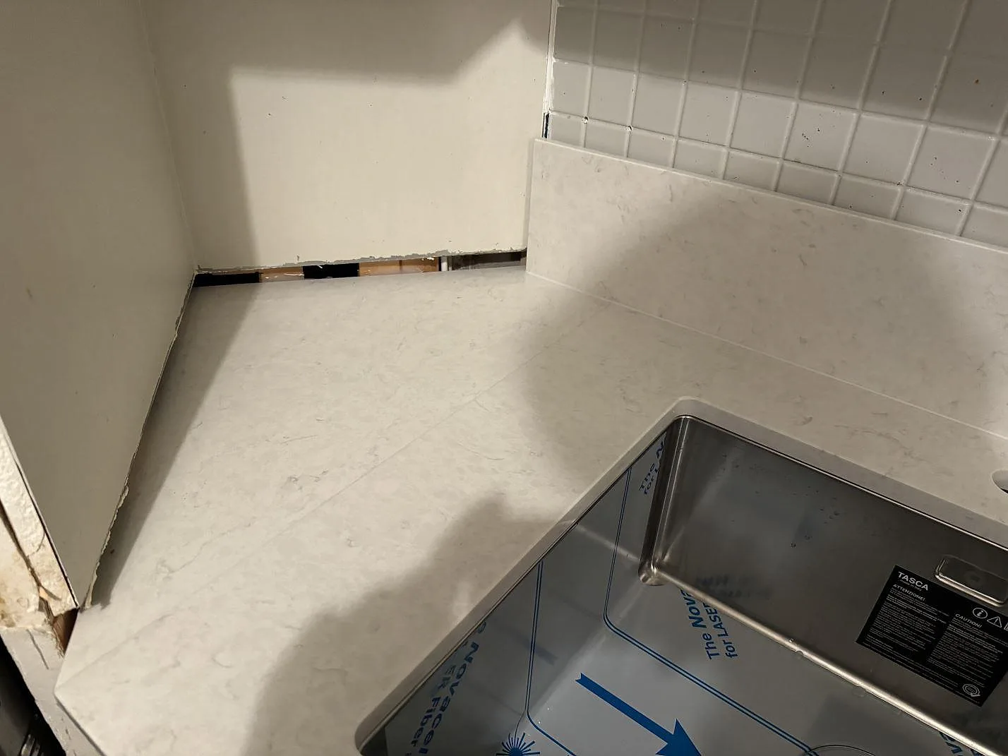 Köksbänk i polerad Silestone Snowy Ibiza med rostfri diskho, låg stänkkant och vägg under renovering i Göteborg.
