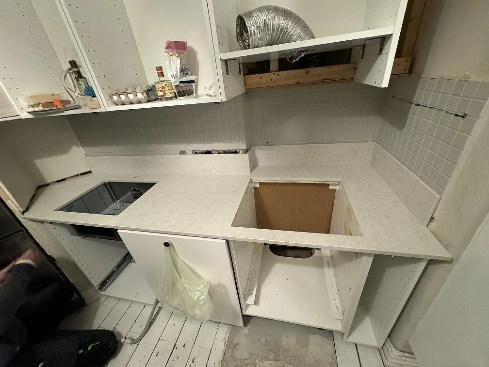Köksbänkskiva i vit polerad Silestone Snowy Ibiza med låg stänkkant, rostfri diskho och öppna köksstommar i Göteborg.