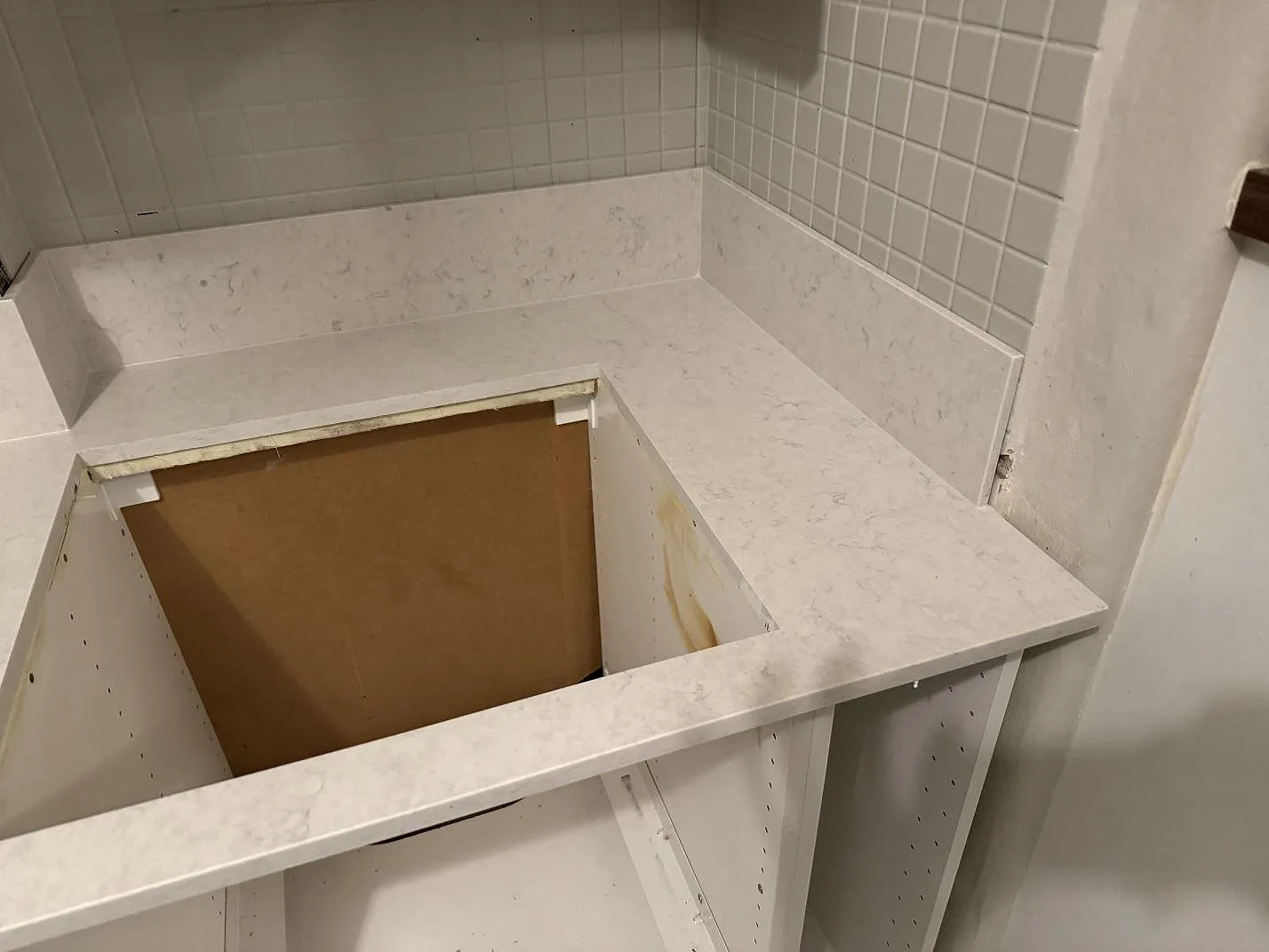 Installerad köksbänkskiva i polerad Silestone Snowy Ibiza med låg stänkkant, vitt kakel och öppna stommar i Göteborg.