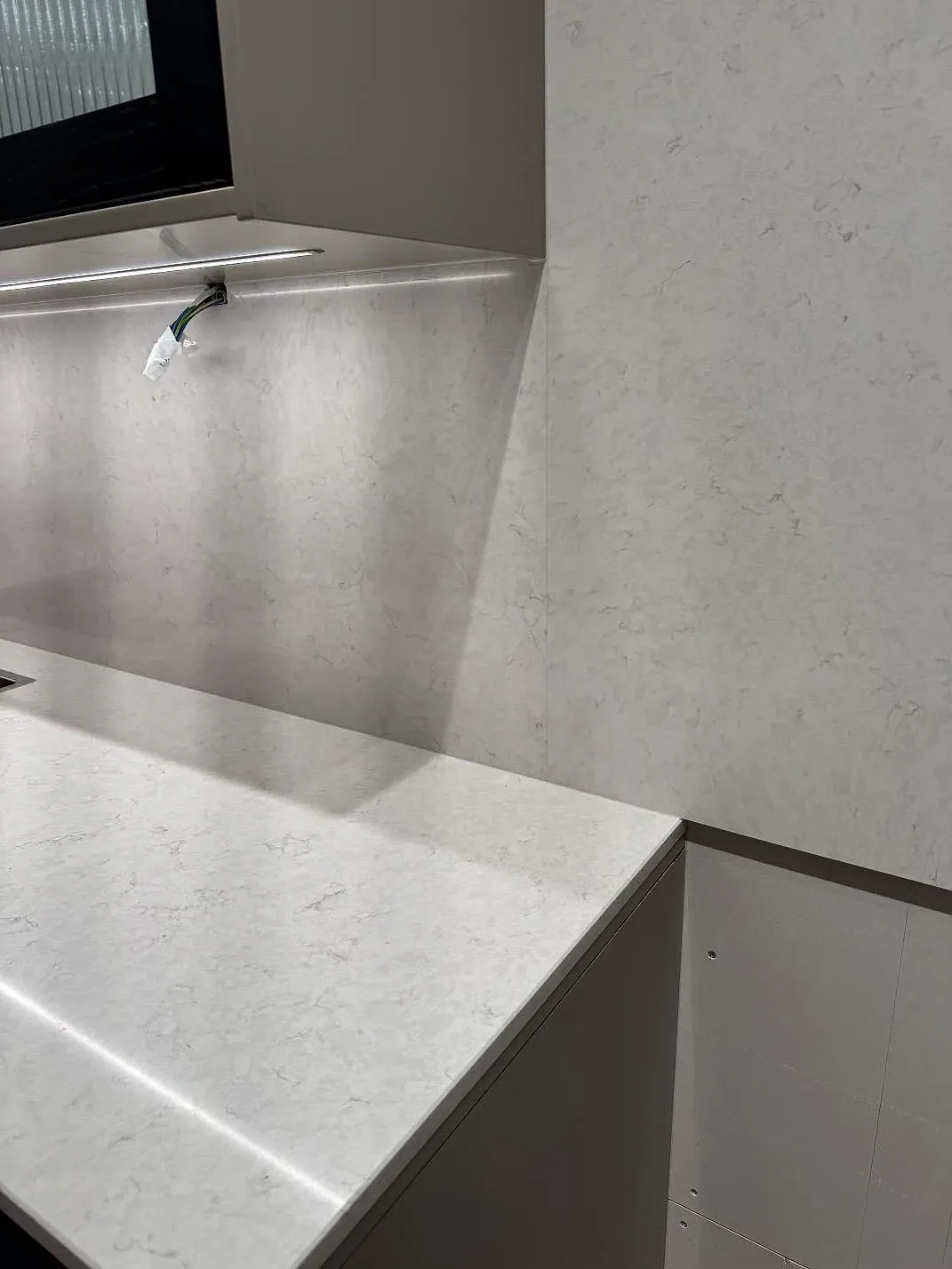 Detalj av polerad Silestone Snowy Ibiza som bänkskiva och väggpanel i ett kompakt kök i Göteborg.