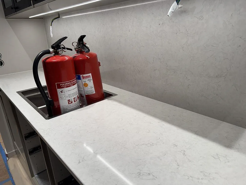 Köksbänk i polerad Silestone Snowy Ibiza med diskhoområde och stänkskydd under montering i Göteborg.