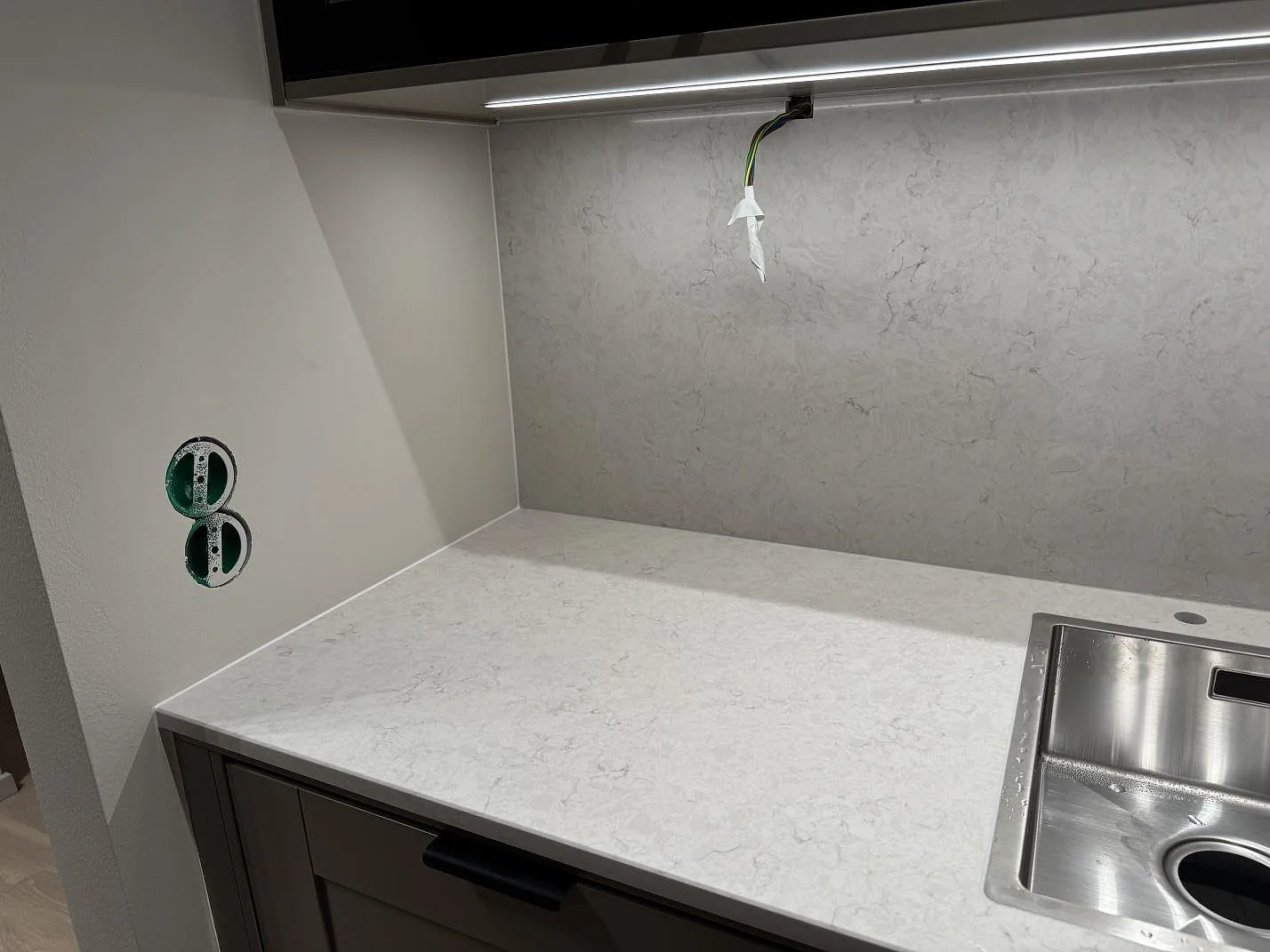 Diskbänksyta med polerad Silestone Snowy Ibiza, kompositsten, och ljus väggbeklädnad i kök i Göteborg.