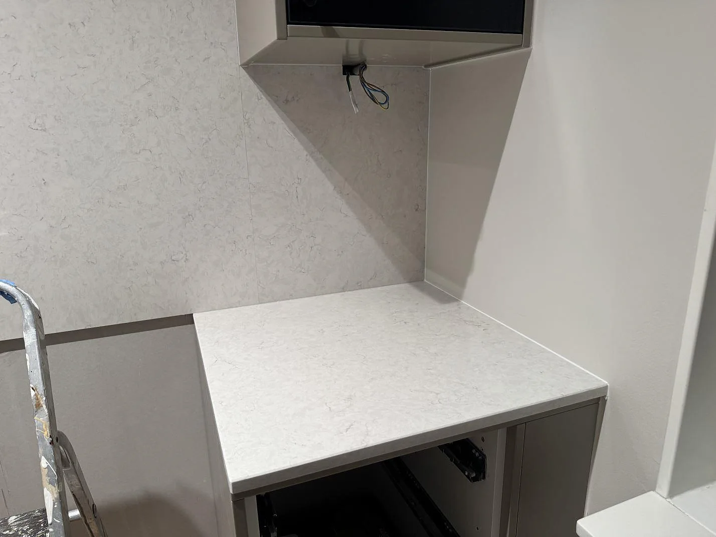 Polerad köksbänkskiva och väggbeklädnad i Silestone Snowy Ibiza, kompositsten, vid arbetsytan i ett kök i Göteborg.