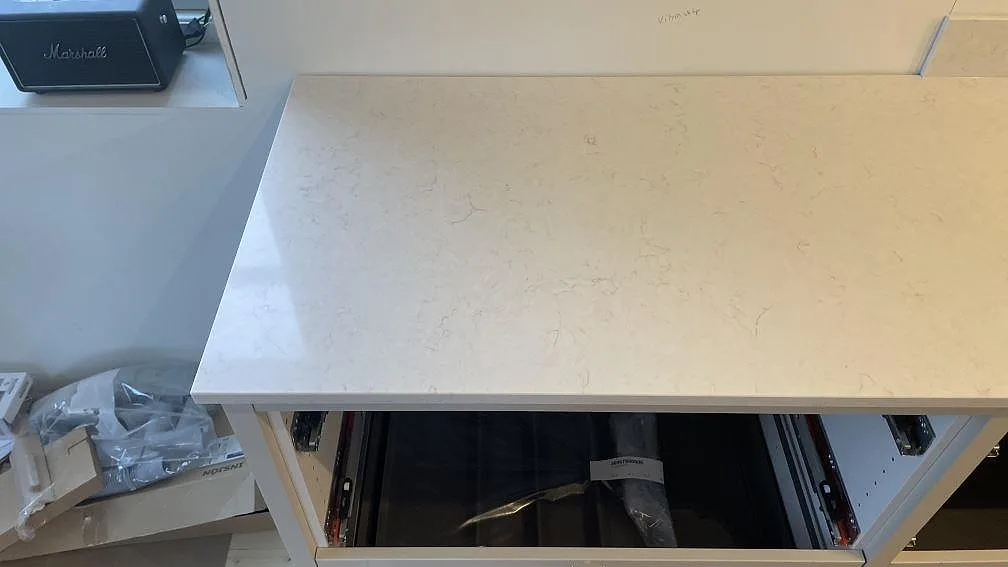 Ytdetalj av vit Silestone Snowy Ibiza-köksbänkskiva, polerad, med mjuk grå ådring och öppen stomme i Gränna.