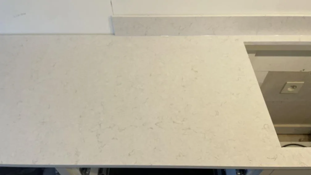 Närbild av polerad Silestone Snowy Ibiza med hällurtag, 12 mm stänkskydd och ljus kompositådring i Gränna.