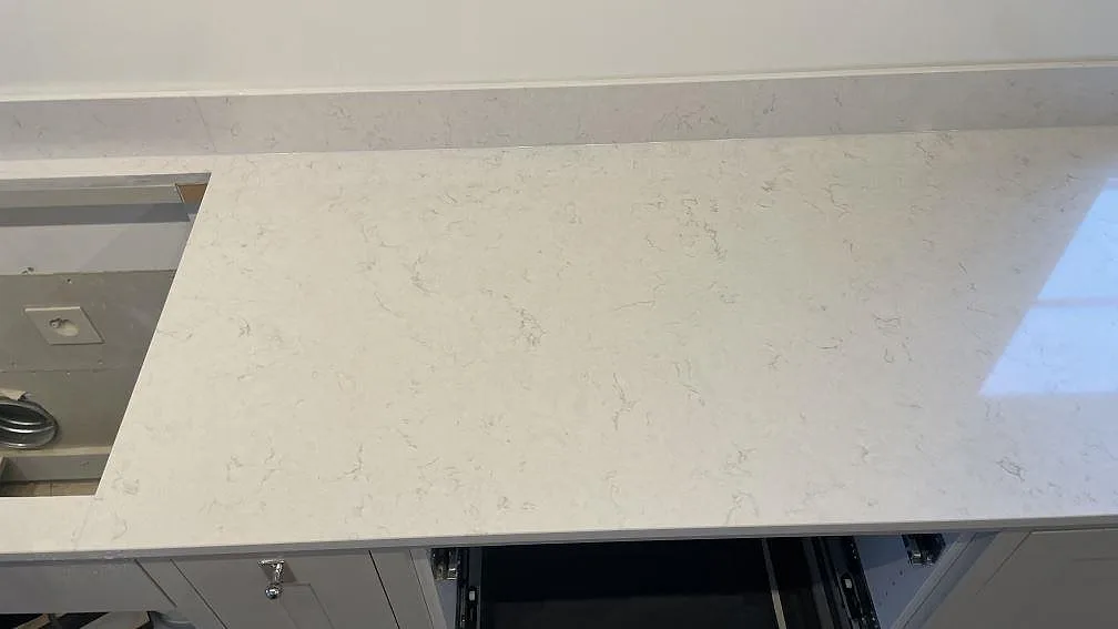 Vit kvartskompositbänkskiva i Silestone Snowy Ibiza med polerad yta, grå ådring och låg stänkkant i ett kök i Gränna.