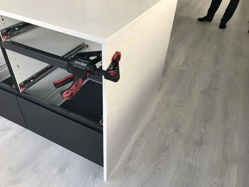 Köksö i vit Silestone Snowy Ibiza med vattenfallskant sedd från sidan i ett kök i Häljarp.