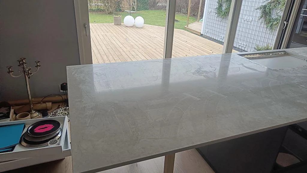 Blank yta i polerad Silestone Snowy Ibiza på stor köksö framför fönsterparti i Häljarp.