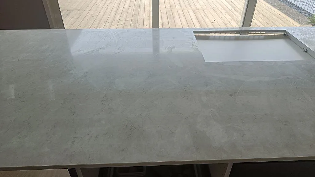 Köksö i polerad Silestone Snowy Ibiza med synligt hällurtag och ljus grå ådring i Häljarp.