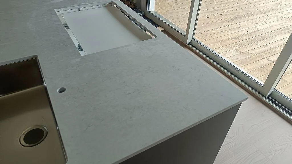 Polerad Silestone Snowy Ibiza med diskho och hällurtag vid stora fönster i köket i Häljarp.