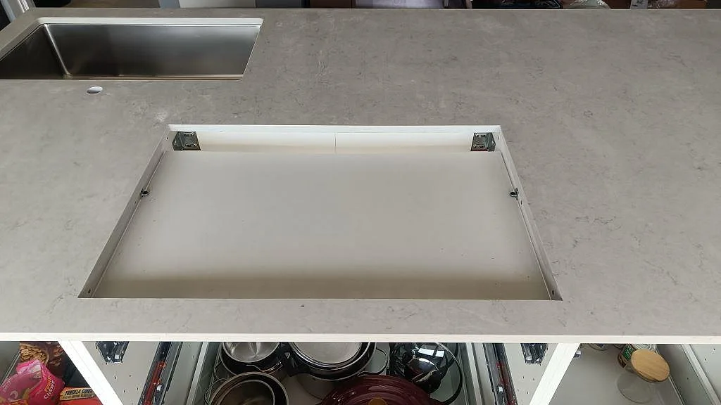 Detalj av hällurtag i polerad Silestone Snowy Ibiza med rostfri diskho längre bak i köket i Häljarp.