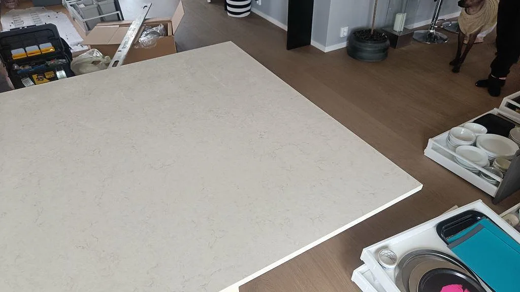 Hörn av stor polerad Silestone Snowy Ibiza skiva med mjuk grå ådring i köket i Häljarp.