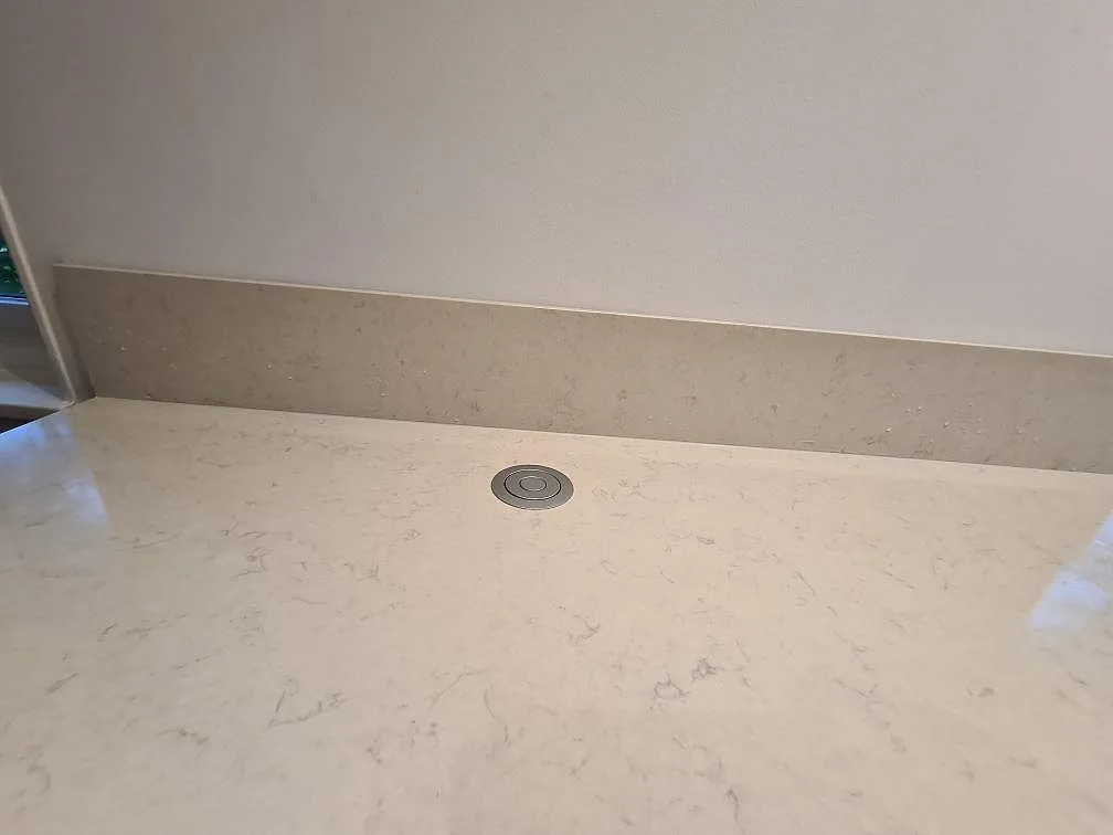 Polerad Silestone Snowy Ibiza som köksbänkskiva med kabeluttag och lågt stänkskydd i ett kök i Hässelby.