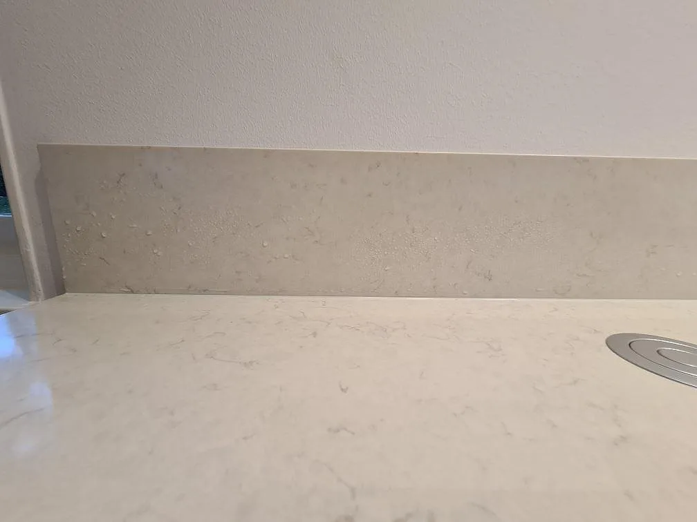 Detalj av 12 mm stänkskydd och polerad Silestone Snowy Ibiza längs väggbänken i köket i Hässelby.