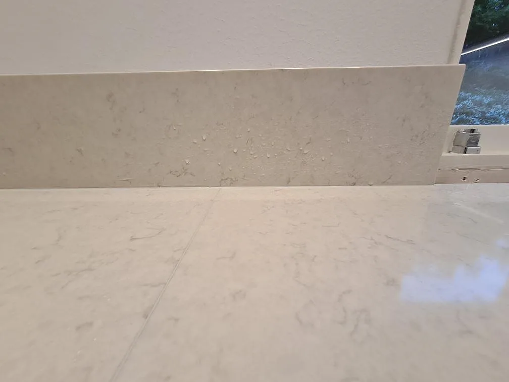 Polerad Silestone Snowy Ibiza med mjuk ådring och lågt stänkskydd intill fönster i ett kök i Hässelby.