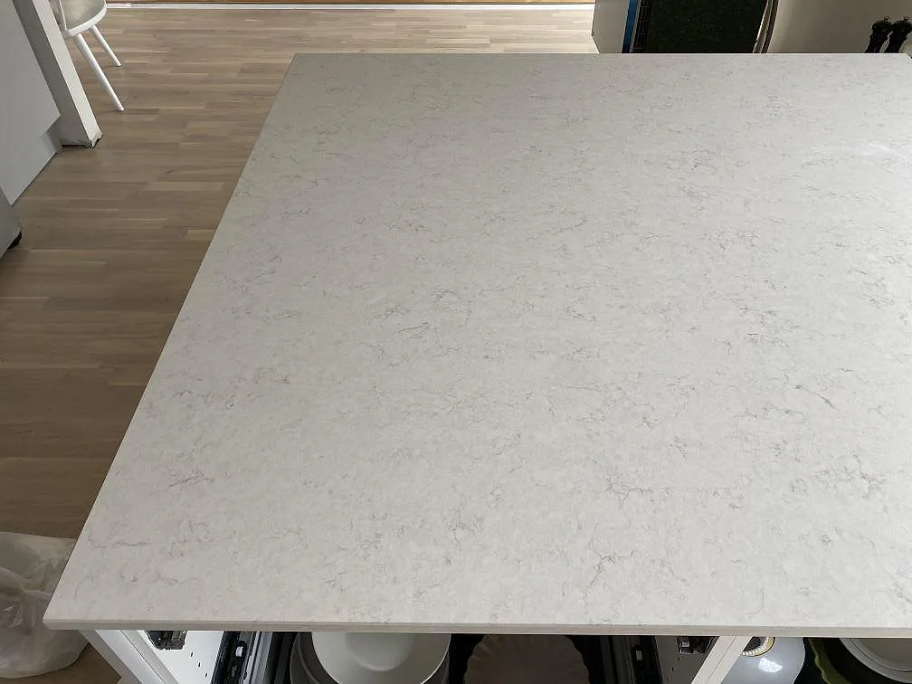 Stor köksö i polerad Silestone Snowy Ibiza med mjukt grå ådring sedd ovanifrån i ett kök i Halmstad.
