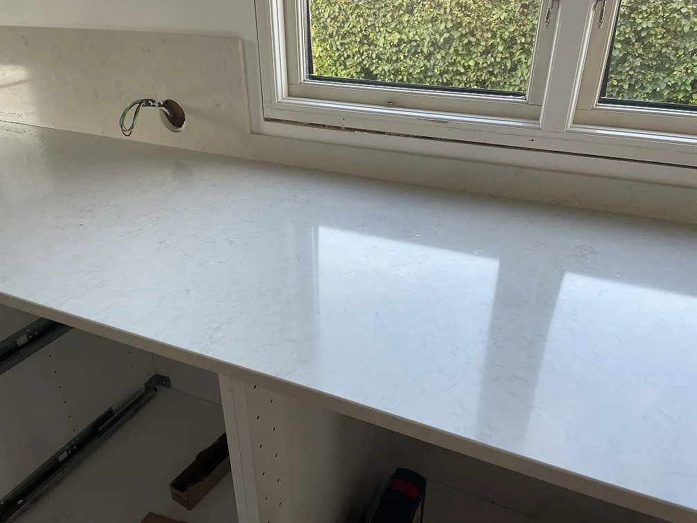 Blank polerad Silestone Snowy Ibiza bänkskiva vid fönster med mjuk grå ådring i ett kök under montering i Halmstad.