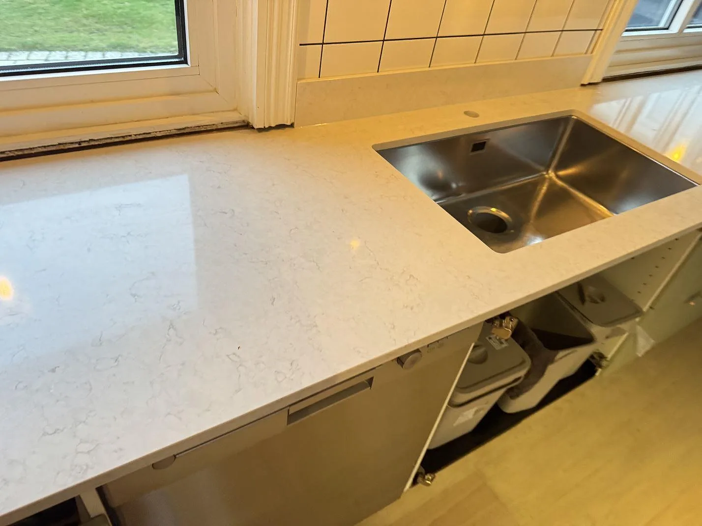 Underlimmad rostfri diskho i en vit Silestone Snowy Ibiza köksbänkskiva med polerad yta och mjuk grå ådring i Halmstad.