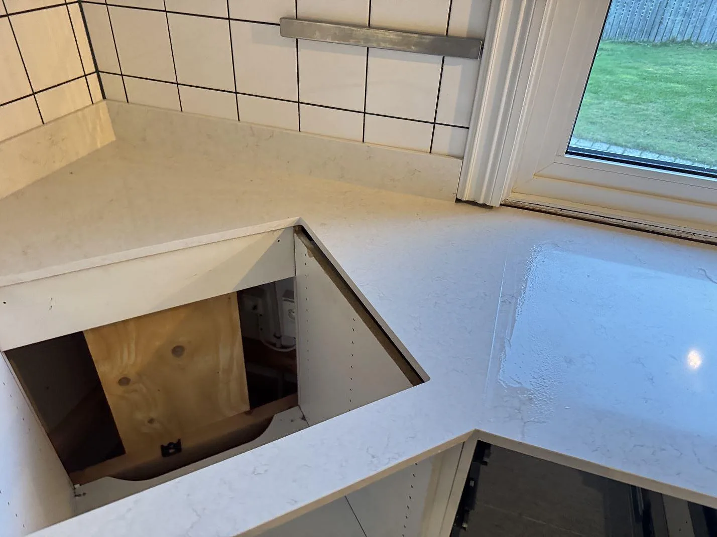 Köksbänk i vit Silestone Snowy Ibiza under montering med utskuren plats för diskho och stänkskydd i vit kakel i Halmstad.