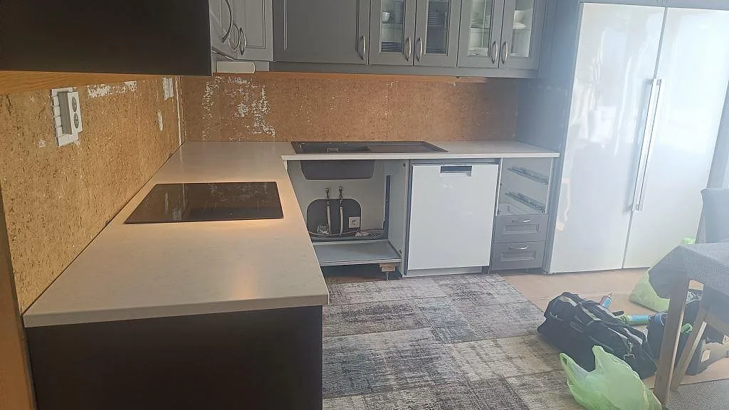 Köksbänkskiva i Silestone Snowy Ibiza, Mocka, med svart häll och underlimmad svart diskho i ett kök under montering i Harestad.