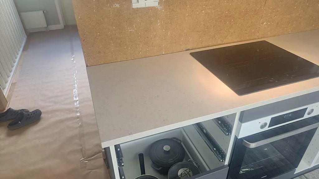 Närbild på matt Silestone Snowy Ibiza som köksbänkskiva med svart häll och grå underskåp i Harestad.