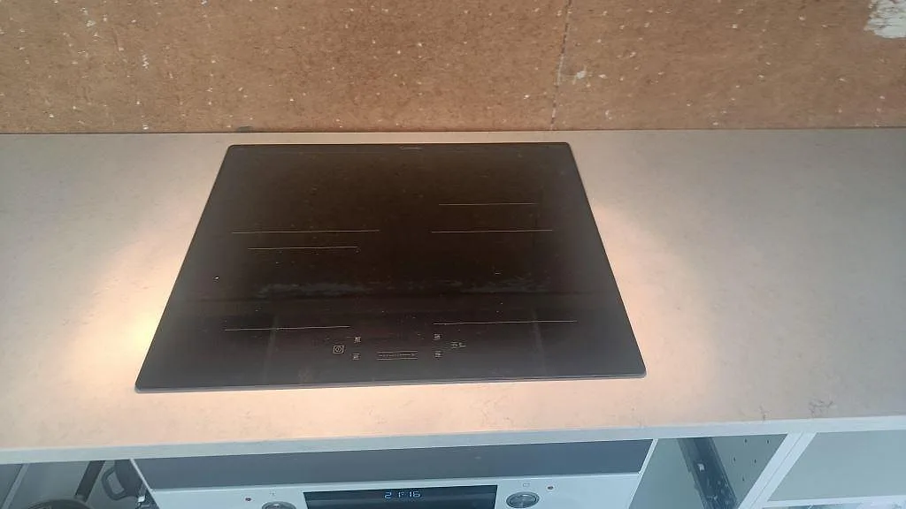 Svart häll monterad i 30 mm Silestone Snowy Ibiza, Mocka, framför OSB-vägg i ett kök i Harestad.