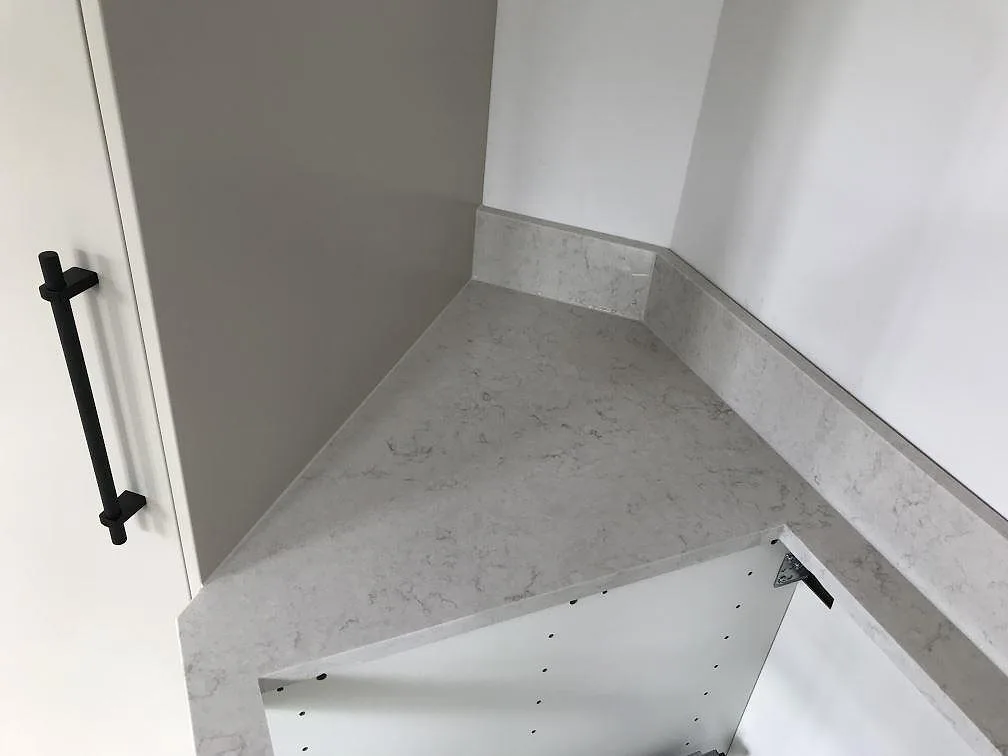Topvy av polerad Silestone Snowy Ibiza köksbänkskiva med stänkkant runt ett hörn i ett kök i Helsingborg.