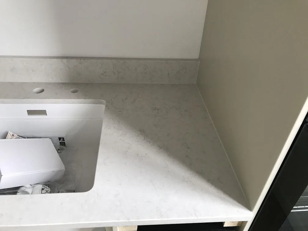 Hörnparti av polerad köksbänkskiva i vit Silestone Snowy Ibiza med stänkkant och svart bygelhandtag i ett kök i Helsingborg.