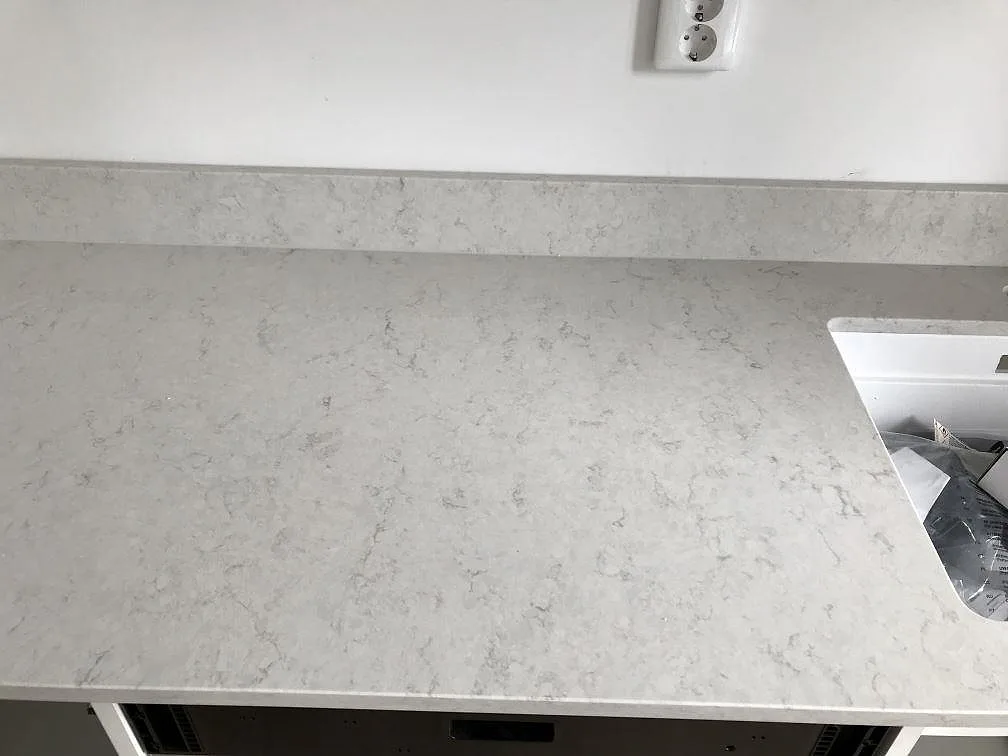 Eye-level vy av installerad köksbänkskiva i polerad Silestone Snowy Ibiza med mjuk grå ådring och uppvikt stänkkant i ett kök i Helsingborg.