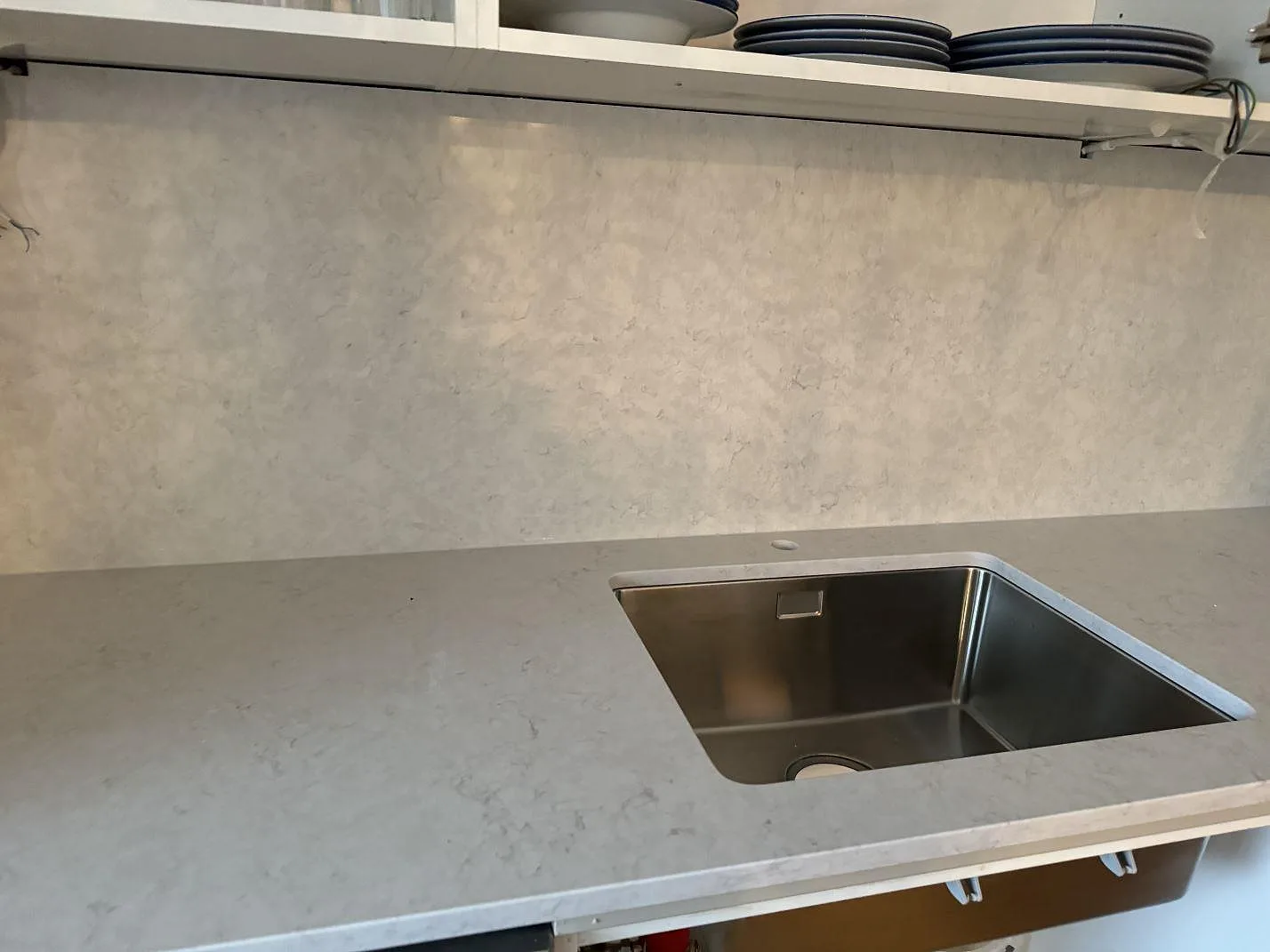 Polerad köksbänkskiva i Silestone Snowy Ibiza med synlig rostfri diskho och hög väggbeklädnad i Helsingborg.