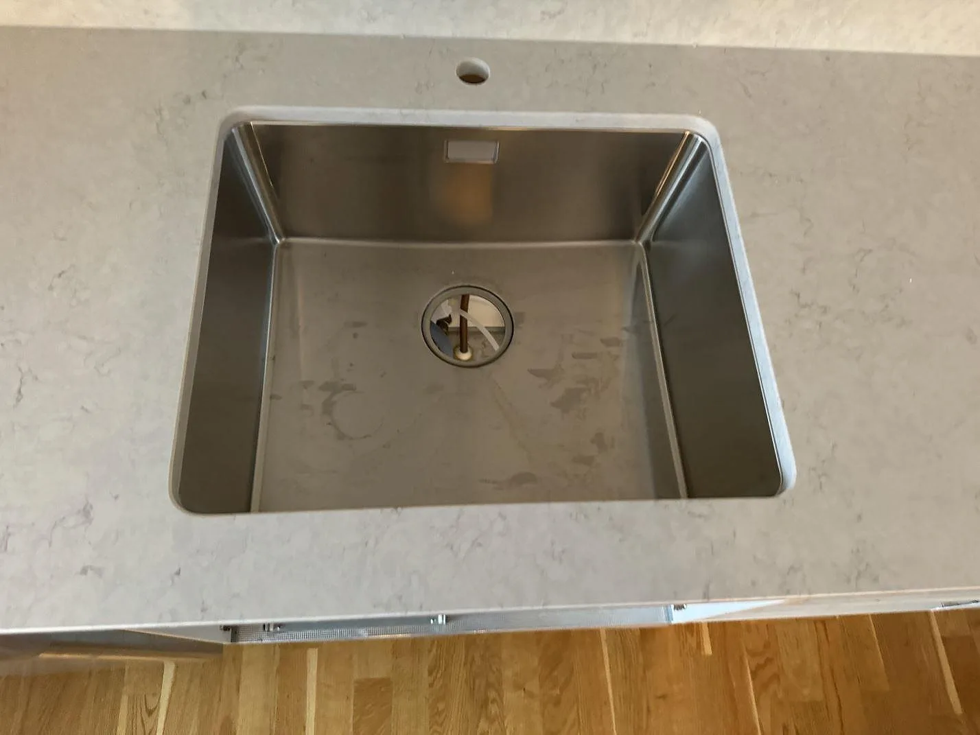 Närbild på rostfri diskho i polerad Silestone Snowy Ibiza med kranhål och ljus ådring i Helsingborg.