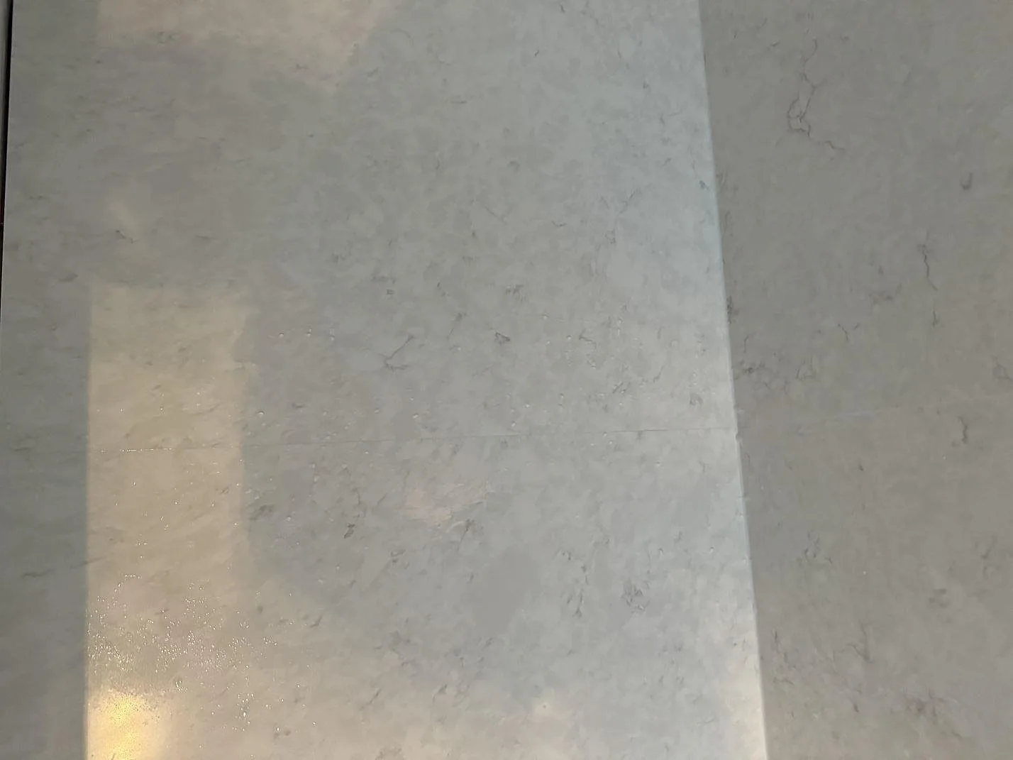 Närbild på den ljusa ådringen i polerad Silestone Snowy Ibiza över bänkskiva och väggfält i Helsingborg.