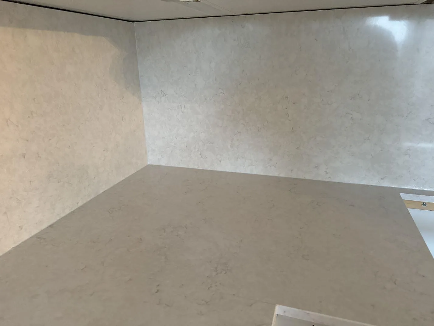 Rak arbetsyta i polerad Silestone Snowy Ibiza komposit med matchande väggfält och synlig diskhozon i Helsingborg.