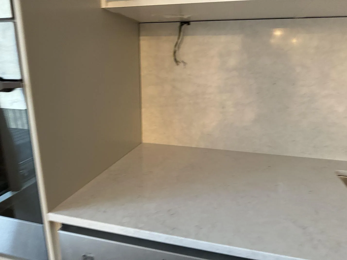 Vänster del av köksbänkskivan i polerad Silestone Snowy Ibiza med väggbeklädnad och öppen montering i Helsingborg.