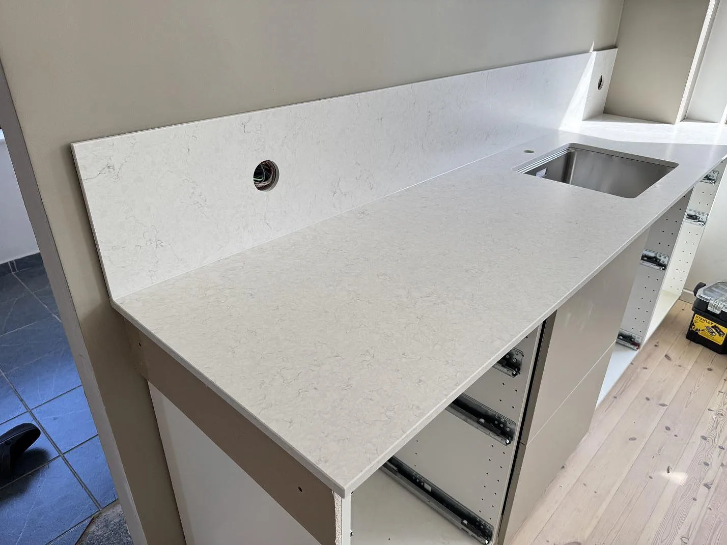 Köksbänkskiva i Silestone Snowy Ibiza Mocka med uppvikt stänkskydd och rostfri diskho i ett kök i Helsingborg.
