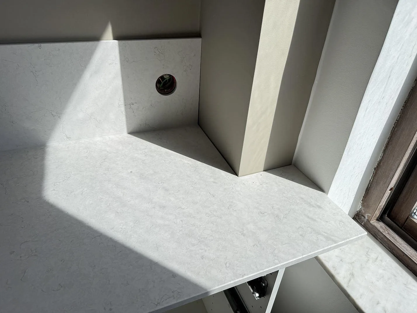 Detalj av Silestone Snowy Ibiza Mocka runt fönsternisch och stänkskydd med ljus ådring i ett kök i Helsingborg.
