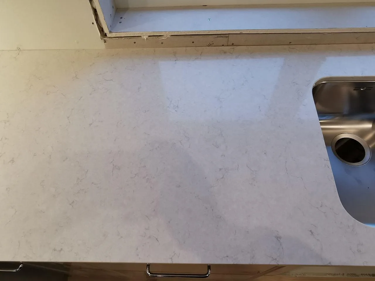 Polerad köksbänkskiva i Silestone Snowy Ibiza med underlimmad rostfri diskho och blandarhål i ett kök i Hindås.