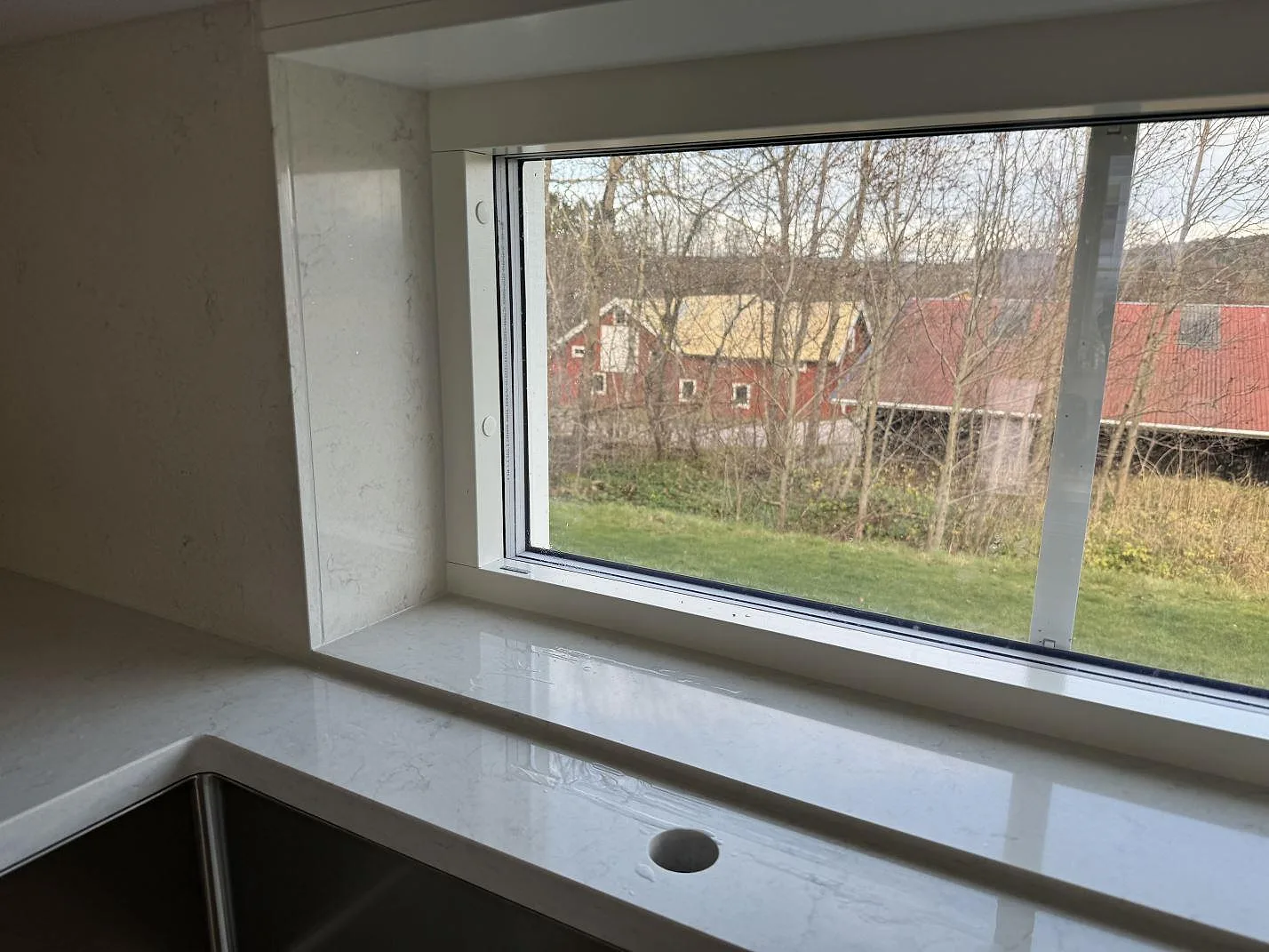 Detalj av polerad Silestone Snowy Ibiza i komposit vid fönster, blandarhål och underlimmad rostfri diskho i Hisings Kärra.