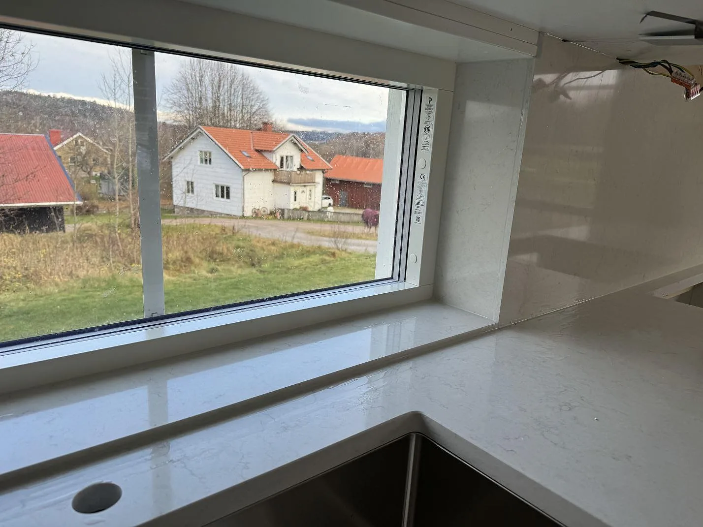 Köksbänkskiva och fönsternisch i polerad Silestone Snowy Ibiza med ljus ådring och utsikt över landskapet i Hisings Kärra.