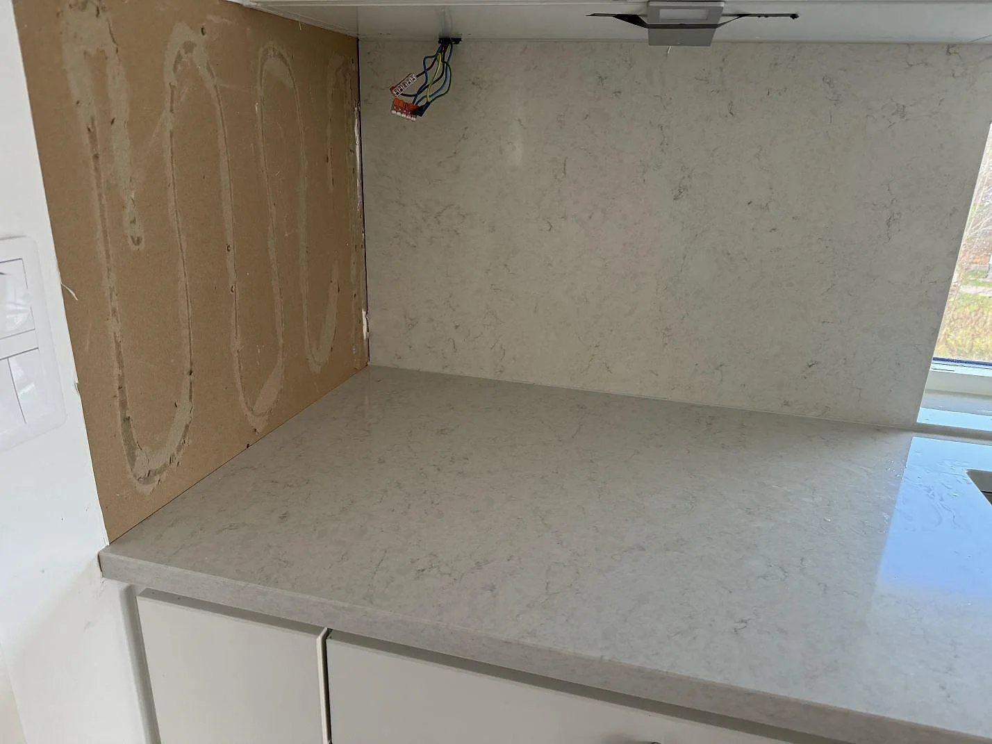 Polerad Silestone Snowy Ibiza som bänkskiva och stänkskydd i ett kök under montering i Hisings Kärra.