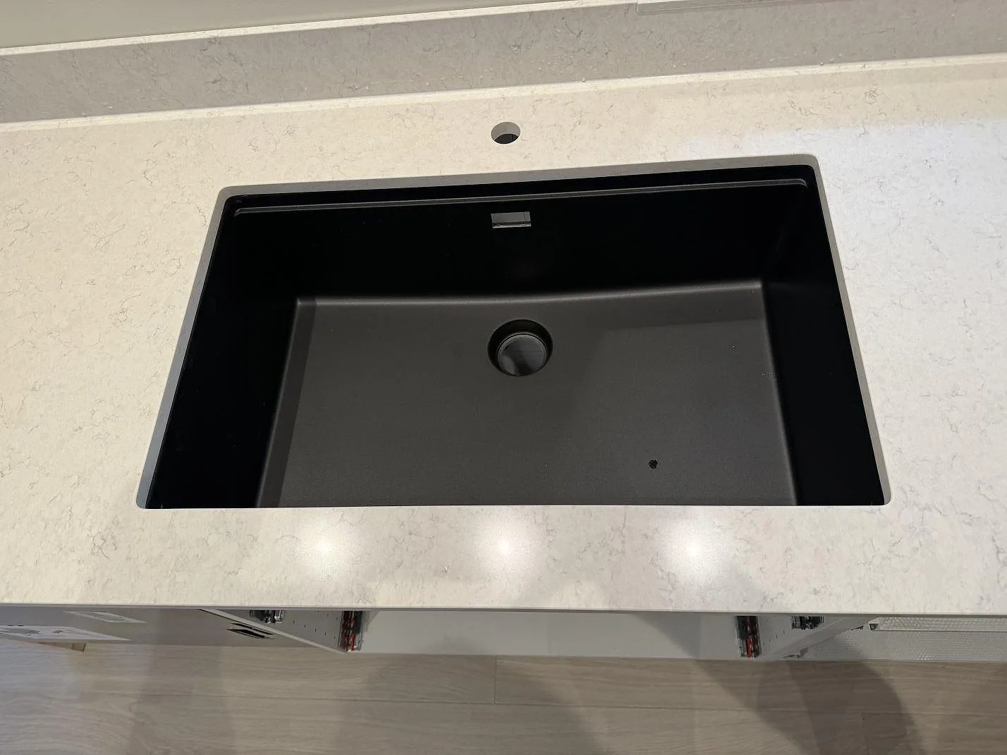 Närbild på svart diskho och ljus kompositbänkskiva i polerad Silestone Snowy Ibiza i köket i Höllviken.