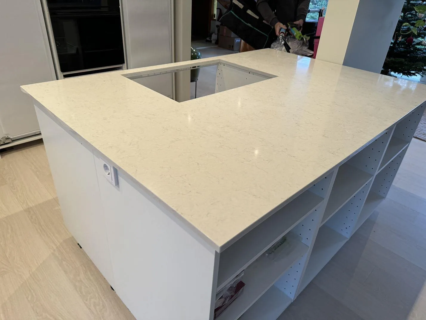 Polerad Silestone Snowy Ibiza på köksö med utskärning för häll och vita köksstommar i Höllviken.
