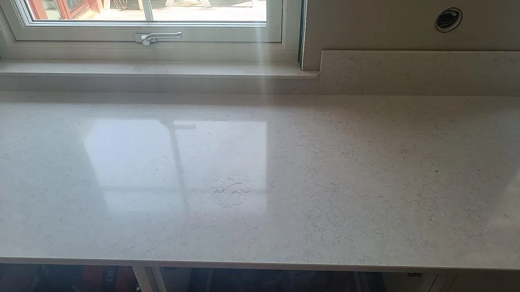Ytbild av ljus Silestone Snowy Ibiza med polerad reflektion från fönster och diskret grå ådring i Höllviken.