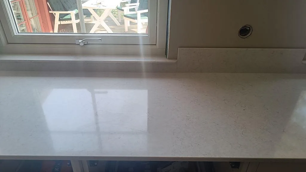 Detalj av Silestone Snowy Ibiza som köksbänkskiva under fönster med eluttag och polerad yta i Höllviken.