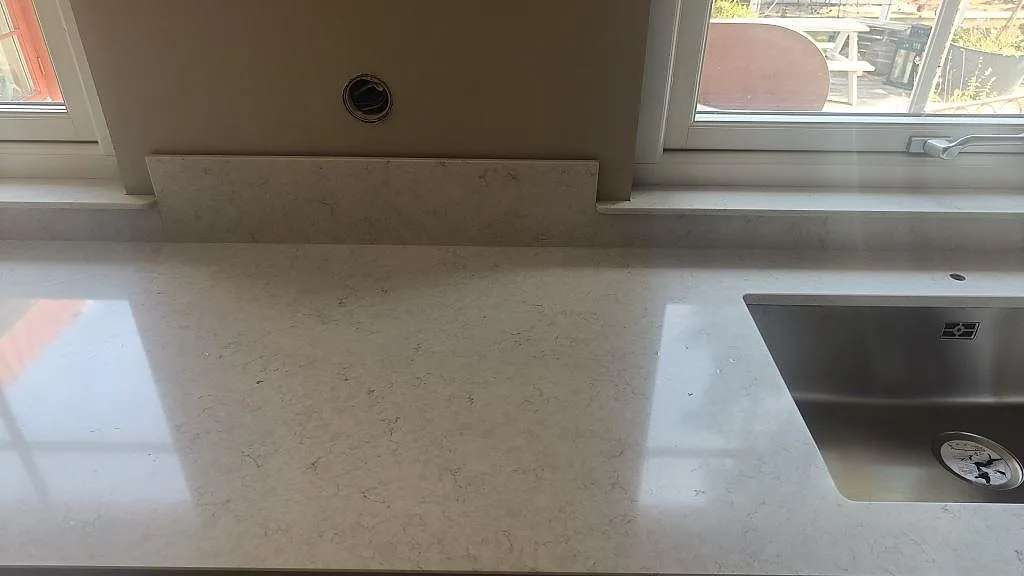 Närbild av polerad Silestone Snowy Ibiza runt underlimmad diskho och 12 mm stänkkant i kök i Höllviken.