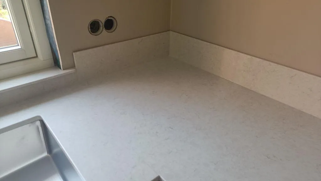Hörndetalj vid diskhon där ljus Silestone Snowy Ibiza möter låg stänkkant och fönsternisch i Höllviken.
