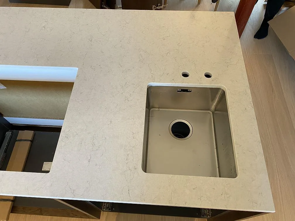 Närbild av polerad Silestone Snowy Ibiza med underlimmad rostfri diskho, borrade hål och intilliggande hällurtag i ett kök i Höllviken.