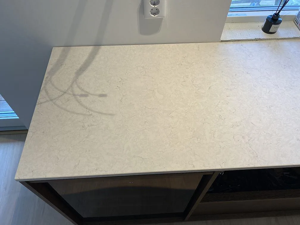 Rak arbetsyta i polerad Silestone Snowy Ibiza under vägguttag och fönster, monterad på mörka köksstommar i Höllviken.