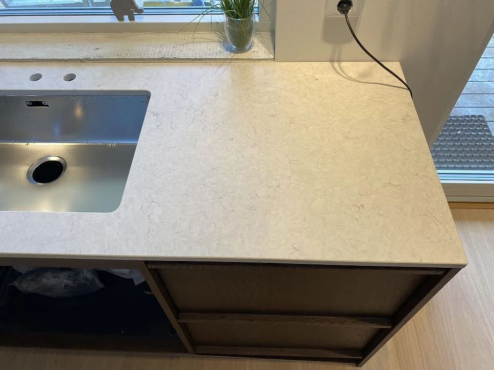 Sidovy av diskzonen med underlimmad rostfri diskho och bred avställningsyta i polerad Silestone Snowy Ibiza i Höllviken.